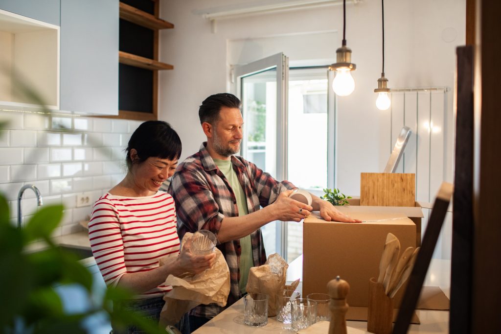 Sellers Happy couple unpacking kitchen items from moving boxes at home